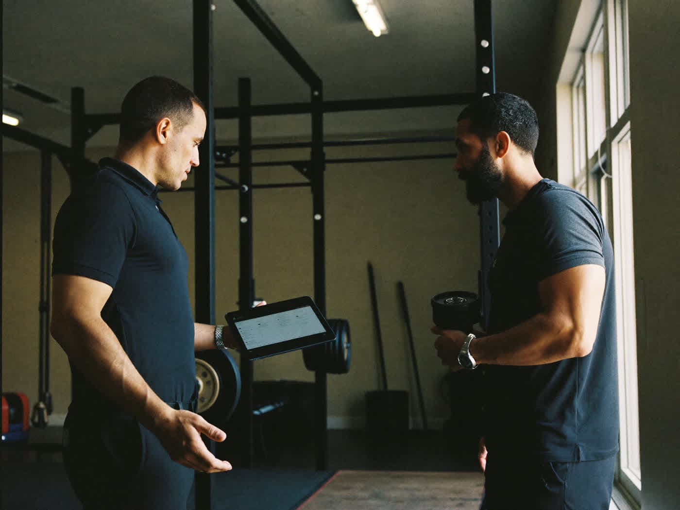 Un entrenador y un socio revisando un plan de entrenamiento en el centro.